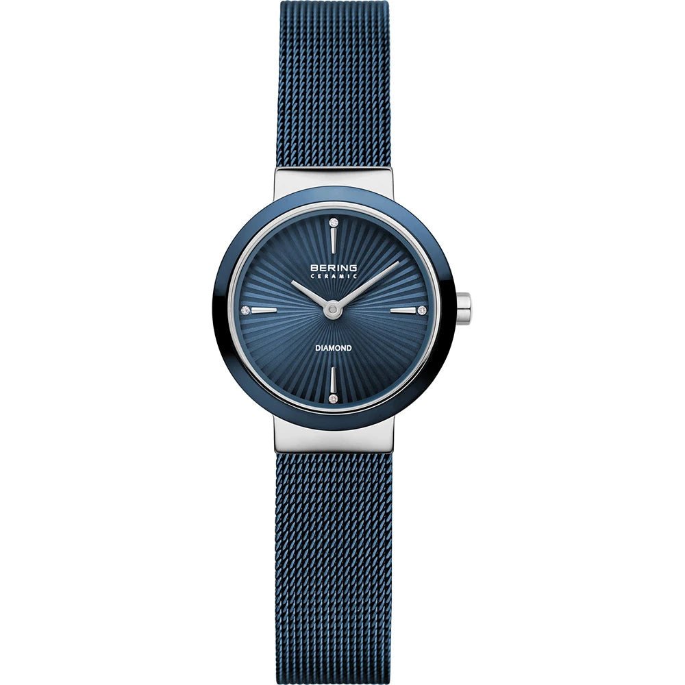 A Bering Watch from the Ceramic Collection (model 10725-307) featuring a blue mesh band, a blue round face with silver hour markers, and a minimalist design. The word "Diamond" appears on the dial, elegantly safeguarded by a scratch-resistant sapphire crystal.