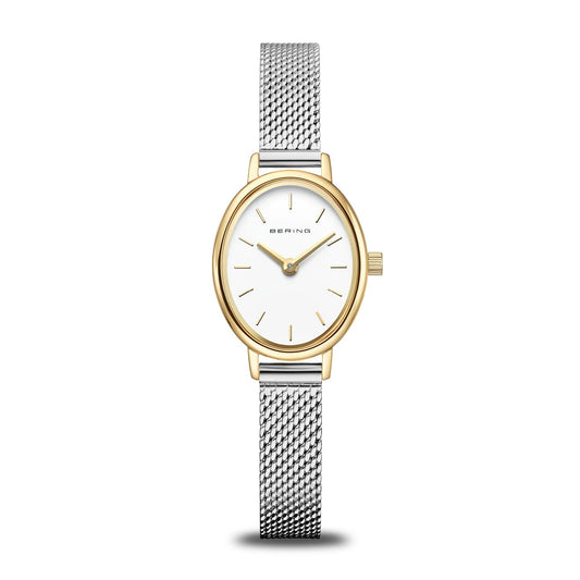 The Bering Watch - Classic Collection 11020-010 is a women's wristwatch featuring a gold oval case, white dial with minimalist gold markers, and a Milanese mesh bracelet. "Bering" is printed on the dial, reflecting timeless Scandinavian design.