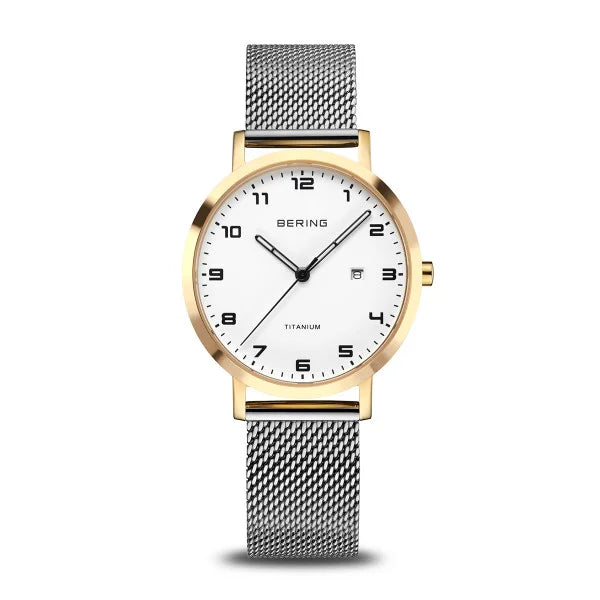 The Bering Watch - Womens Titanium - 18634-010 features a silver mesh strap, gold bezel, white face, black numerals and hands, date display, sapphire crystal, and TITANIUM above 6 o’clock. Brand: Bering.