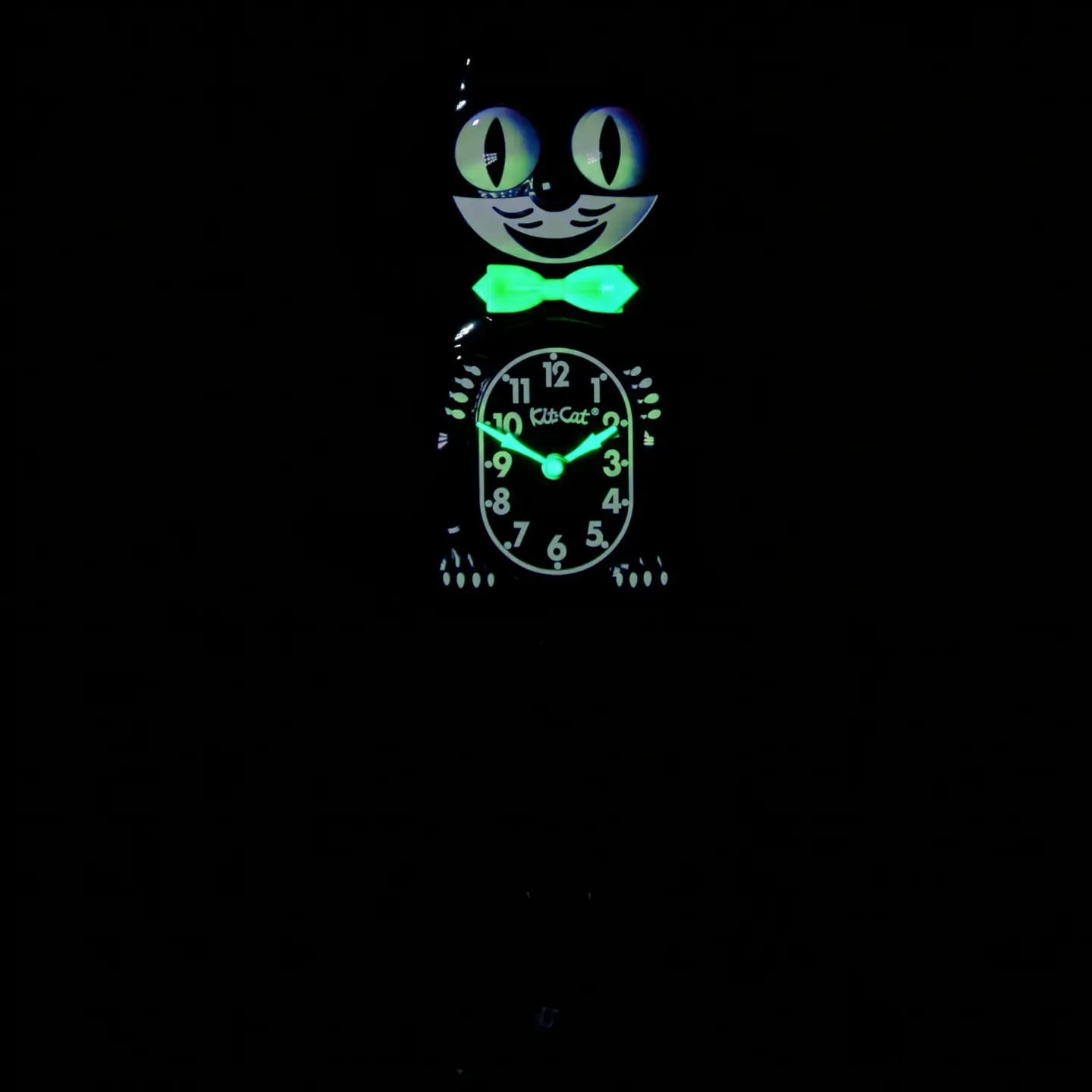 The California Clocks Kit-Cat Klock - Classic Black Gentleman Glow Edition (BC-1 GLOW) features a bow tie and glowing eyes that stand out in the dark. Illumined with a greenish light, its face and details make it easy to read the time—around 9:03—even at night.