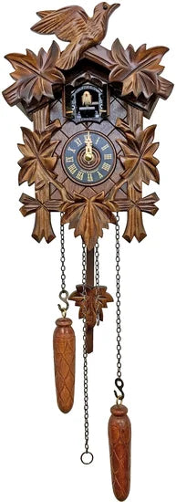 The Alexander Taron Inc. Engstler Black Forest Carved Cuckoo Clock (522QM) features leaf carvings, a bird on top, two pinecone weights on chains, and a clock face with Roman numerals and small hands.