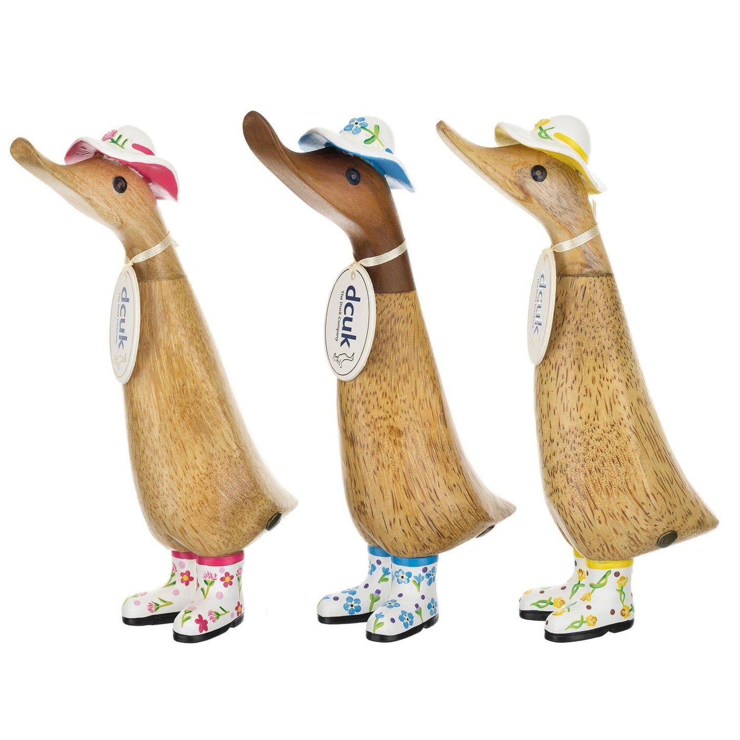 Three Enesco DCUK Ducklings (Duckling White Hat & Boots Floral - 6019177) stand in a row, each hand-carved from bamboo with floral hats and boots. Their smooth finish and quirky poses add a charming touch to any space.