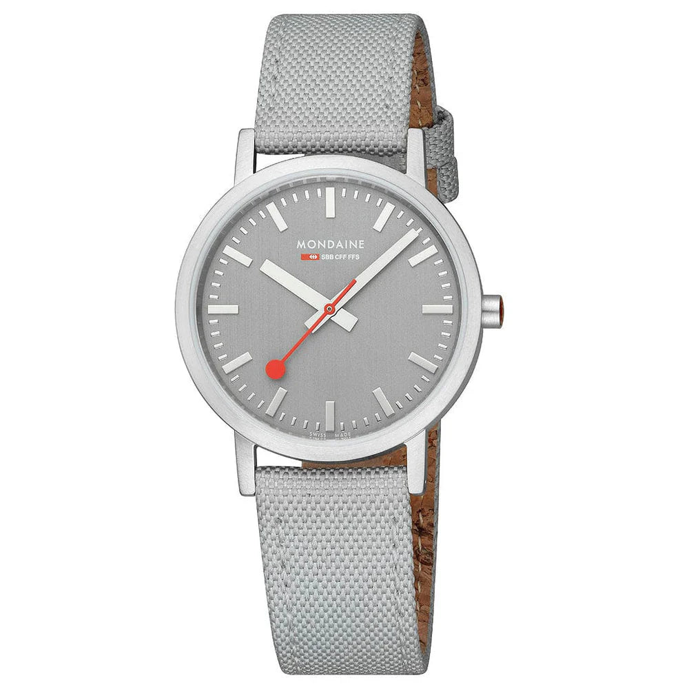 The Mondaine Watch - Good Grey Dial with Textile Strap (A660.30314.80SBH) features a silver case, grey dial, white hour markers, red-tipped second hand, and light grey strapโall in a timeless minimalist Swiss design inspired by the iconic railway watch.