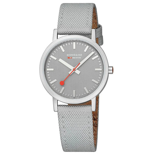 The Mondaine Watch - Good Grey Dial with Textile Strap (A660.30314.80SBH) features a silver case, grey dial, white hour markers, red-tipped second hand, and light grey strap—all in a timeless minimalist Swiss design inspired by the iconic railway watch.