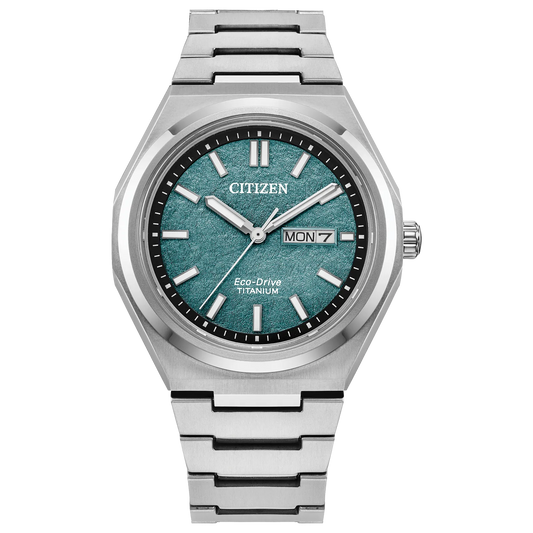 The Citizen Watch - Zenshin Three-hand (AW0130-85X) features Super Titanium, an Eco-Drive movement, a textured teal dial with silver markers and hands, day-date display at 3 o’clock, and a sleek silver metal bracelet.