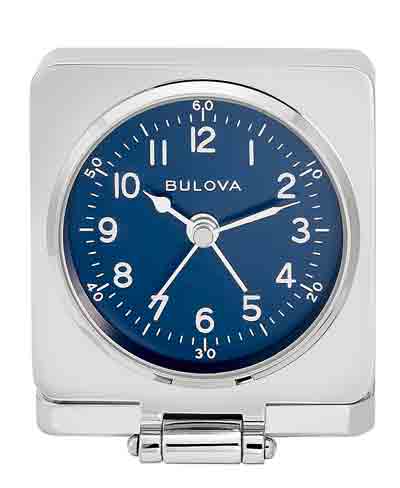 The Bulova Clock - Travel Hack - B1882 is a square silver travel alarm clock with a blue face, white hour marks and hands, displaying 3:14:26. The clock is propped open on its hinged base for portability.