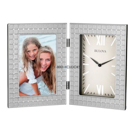 The Bulova Clock - Picture Frame Clock (B6213) features a silver hinged design with a textured square pattern, a Bulova clock with Roman numerals on the right, and space for a photo on the left.