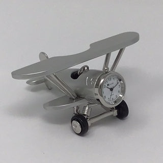 The Sanis Enterprises Sanis Mini Clock - Biplane (C3569S) is a small silver desk clock designed as a biplane model with a clock face on the front, perfect as a decorative piece, shown against a plain white background.