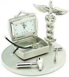 The Sanis Enterprises Sanis Mini Clock - Doctor - CK481 features a silver doctor's bag design with a stethoscope, reflex hammer, otoscope, and caduceus symbol on a round base—perfect as a medical-themed gift or Doctor Clock.
