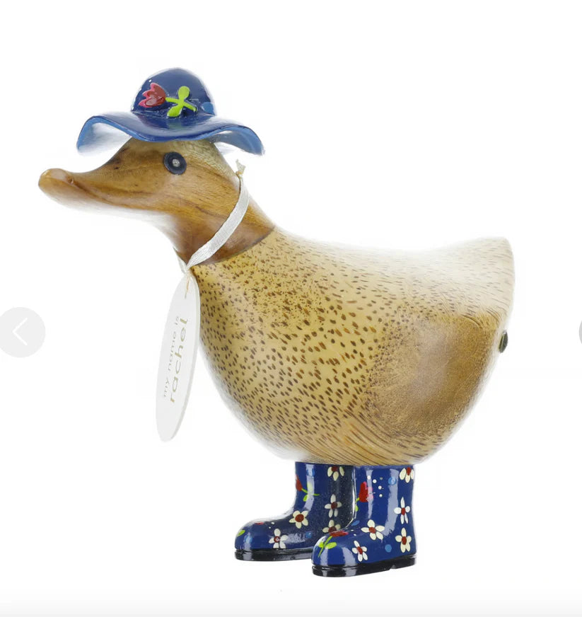 The Enesco DCUK Ducks - Floral Hat and Boots 6 figurine (6017107) is hand-crafted, featuring a blue hat with a red flower, blue boots with white flowers and dots, a speckled body, and a charming white neck tag.