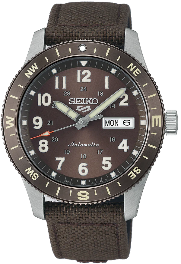 The Seiko Watch - Seiko 5 Automatic - HDB009 by Seiko features a brown dial, silver hands and markers, day-date at 3 o’clock, compass bezel with beige lettering, automatic movement, and a brown fabric strap.