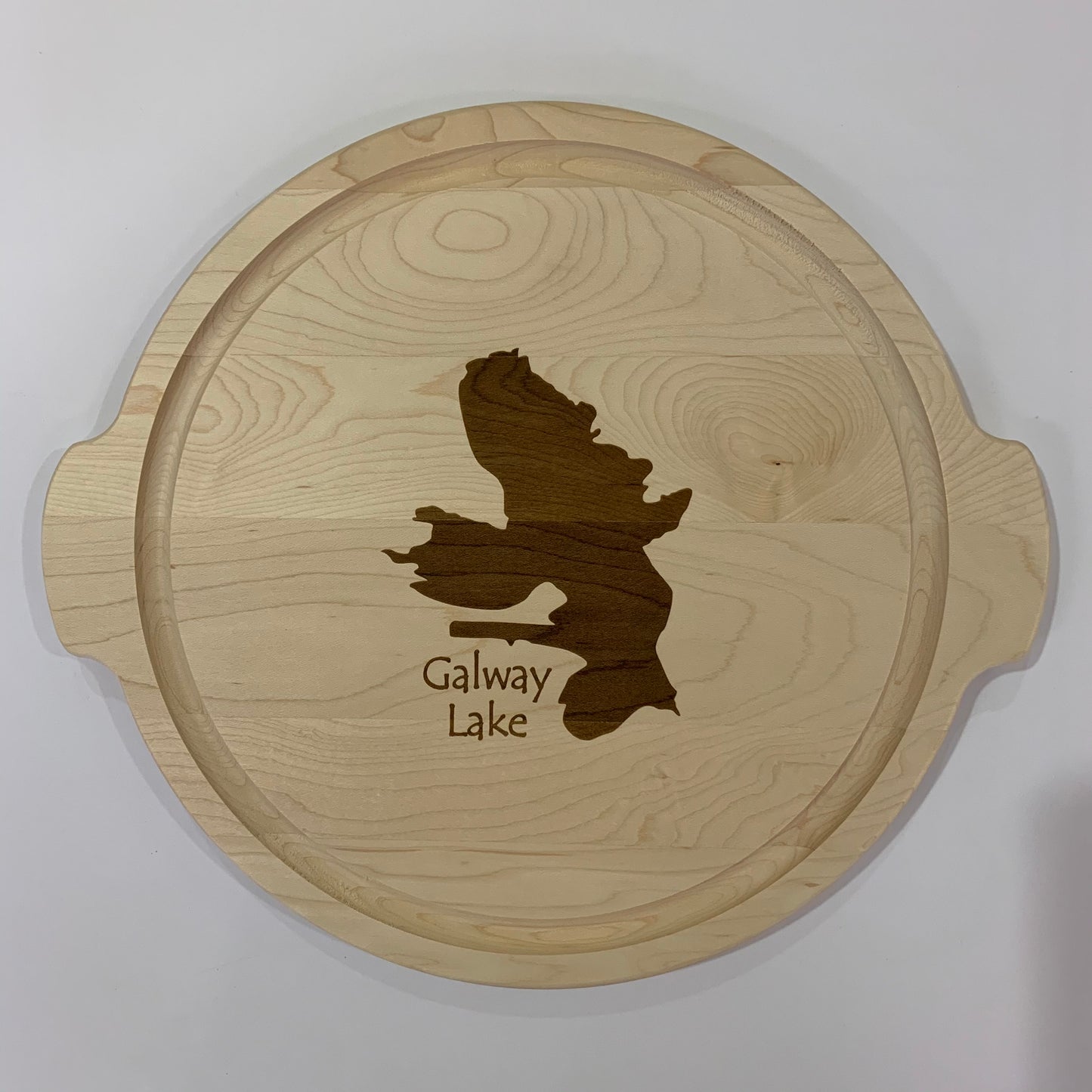 The TS Cutting Board by Time Square Clock Shop is a round custom lake cutting board featuring a laser-engraved Galway Lake design with side handles and "Galway Lake" text, perfect for any home.