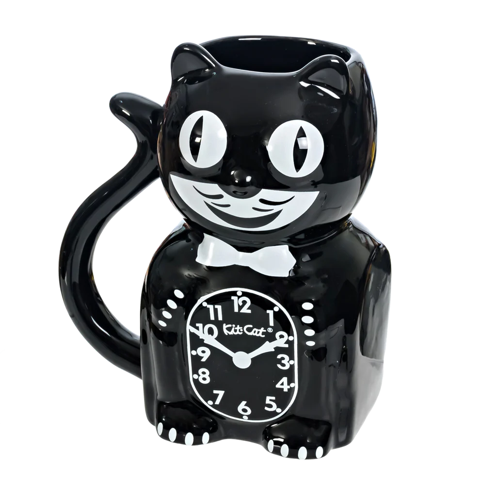 The California Clocks Kit-Cat 20oz Mug (KC-MG-1) features a glossy black ceramic design shaped like a smiling cartoon cat with big eyes, a bow tie, and a clock face on its belly. The handle is the curled tail, inspired by the classic Kit-Cat Klock.