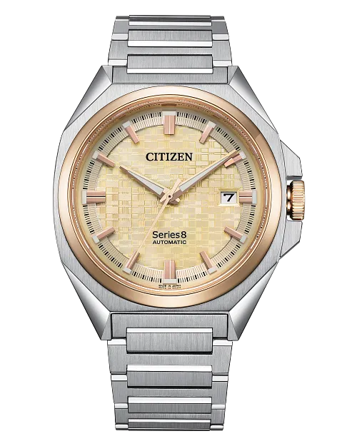 The Citizen Watch - Series8 831 - NB6059-57P features an automatic movement, stainless steel case, silver metal band, gold bezel, textured gold dial with gold hands and markers, plus a date display at 3 o’clock.