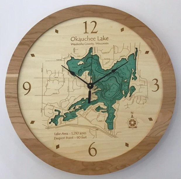 The Lake Art Lake Clock - Okauchee Lake features a wooden frame, an engraved map with depth contours of Okauchee Lake in Waukesha County, Wisconsin, and displays the time as 5:00.