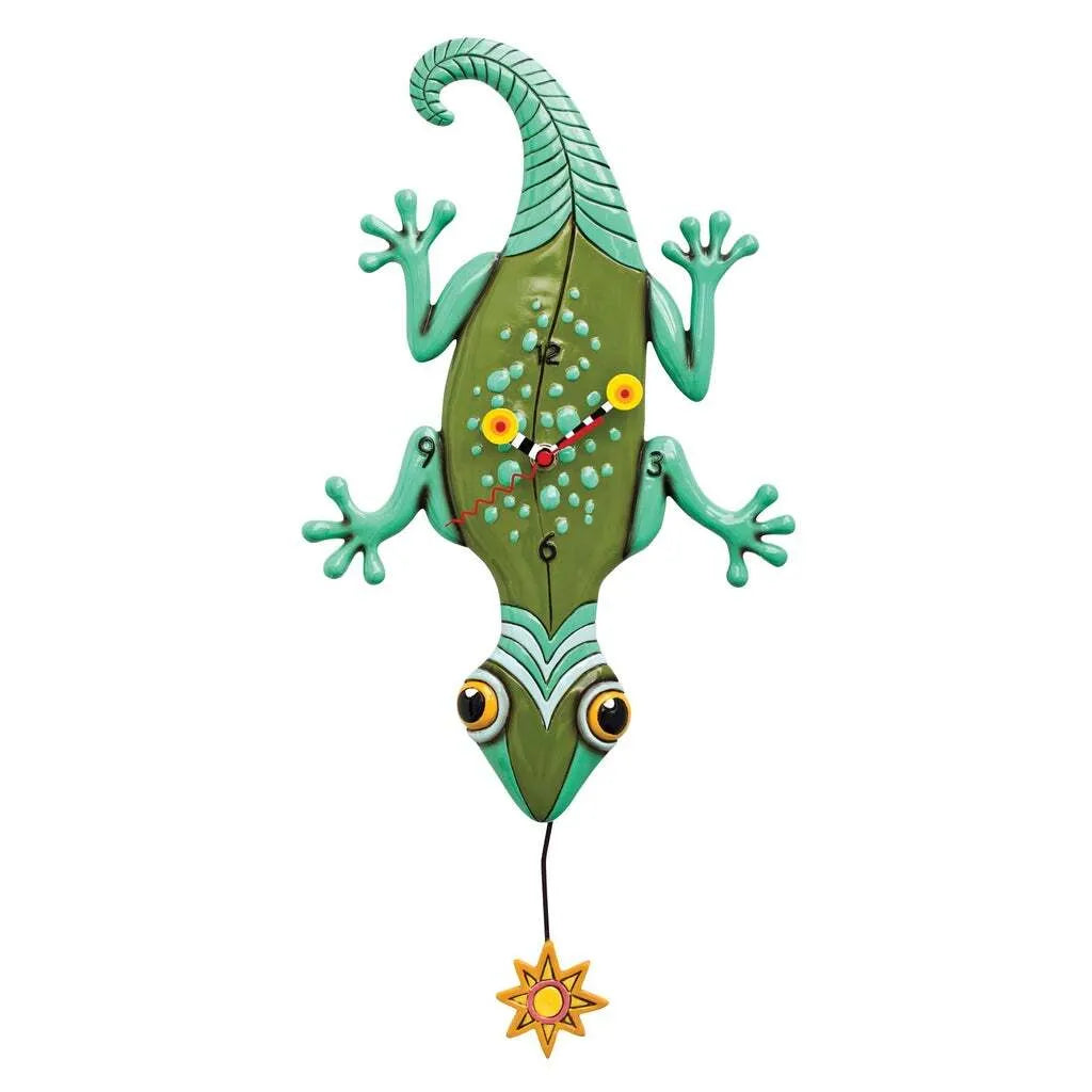 The Enesco Allen Designs Clock - Sun Lizard (P1510) features a green lizard with yellow eyes, blue spots, and an orange star pendulum. Red hands and numbers add a quirky touch—perfect for whimsical lizard gifts or unique decor.