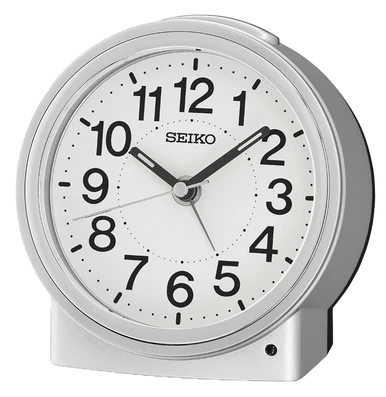 A round, silver Seiko Clocks Bedside Alarm (QHE199SLH) features a white face with bold black numbers and hands, displaying the time as 1:51. With its quiet-sweep second hand for silent operation and simple, modern design, this Seiko bedside alarm clock offers both style and functionality.