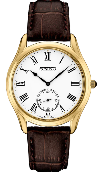The Seiko Essentials SRK050 watch features a gold finish, white dial with black Roman numerals and hands, small seconds sub-dial at 6 o'clock, and a brown leather strap with crocodile pattern.