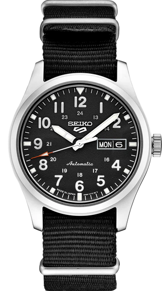 The Seiko 5 Sports SRPG37 by Seiko features a black dial with white numerals, silver hands, day-date at 3 o’clock, dual 12/24-hour markings in military style, and a black nylon strap.