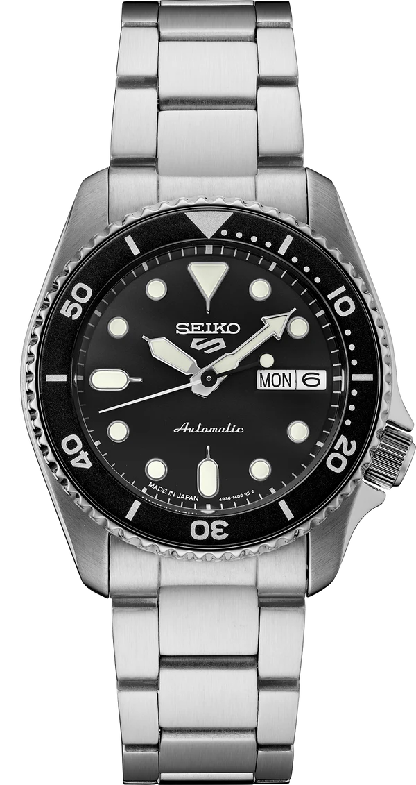 The Seiko 5 Sports SRPK29 is a stainless steel automatic watch with a black dial, luminous markers, rotating bezel, and day-date display at 3 o’clock. The mid-size SKX design shows 10:09 with Monday set on the day display.