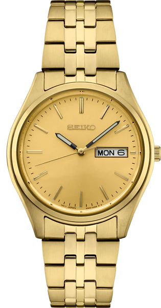 The Seiko Essentials SUR434 features a gold-tone stainless steel case and band, a champagne sunray dial with gold hour markers and hands, plus a day-date window on the right.