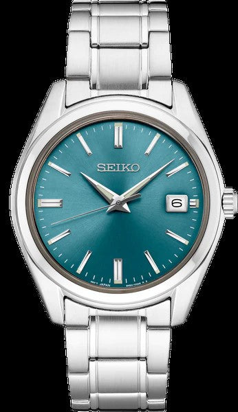 The Seiko Watch - Essentials - SUR525 features a stainless steel case, blue sunray dial with silver markers and hands, date window at 3 o’clock, and a metal link bracelet.