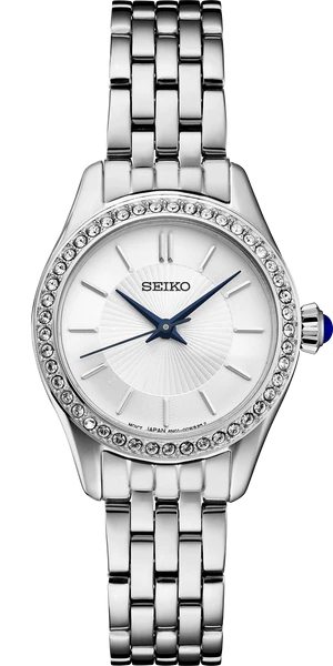 The Seiko Watch - Essentials - SUR539 for women features a stainless steel silver bracelet, round face, bezel with clear crystals, white dial, blue hands, and a crown with a blue accent. Brand: Seiko.