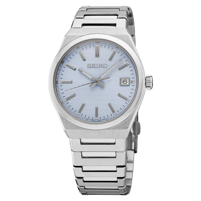 The Seiko Essentials SUR599 watch features a silver stainless steel bracelet, light blue textured dial, silver markers and hands, plus a date window at 3 o’clock.