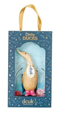 A boxed gift set featuring the Enesco DCUK Ducks - Spotty Boots Dinky Duck (6017104), a hand-carved duck with a white tag and pink spotty boots, displayed in blue floral packaging with a clear window.
