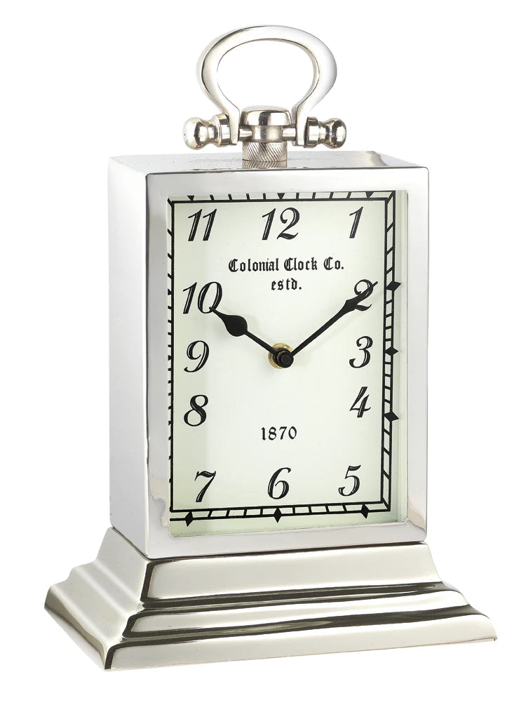 The A Sanoma - Unique Clock - KG320 features a vintage nickel finish, black numbers and hands set at 10:10, Colonial Clock Co. estd. 1870 on the face, plus a decorative top and tiered base for classic charm.