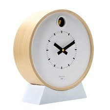 The Cloudnola Dot White Cuckoo Clock (SKU0262) features a light wooden frame, white face, black hands, playful bird detail at the top, and a sleek triangular base—a minimalist wall clock blending simplicity with fun design.