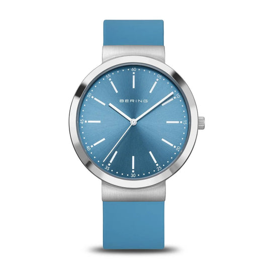 The Bering Watch - Classic Collection - 10141-398 is a minimalist women’s watch with a blue face and strap, silver hour markers and hands, sapphire crystal, silver bezel, and the BERING name at the top of the dial.