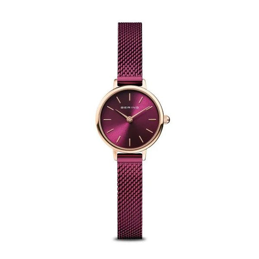 The Bering Watch - Classic Collection Womens Rose Gold w/Purple (11022-969) features a slim purple Milanese strap, round burgundy dial with gold markers, gold case, and the Bering name on the face.
