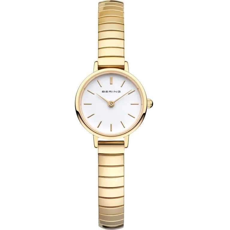 The Bering Watch - Ladies Classic Collection - 11028-934 by Bering features a slim gold metal band and a round white face adorned with gold hour markers and hands set to 12:04. This elegant ladies' watch is completed with a durable sapphire crystal, offering lasting clarity and sophistication.