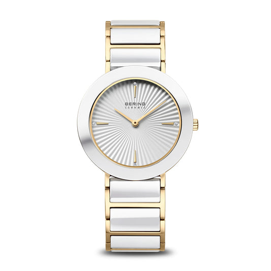 The Bering Watch - Polished Gold - 11435-758 features a gold and silver metal band, round silver sunburst face with minimalist markers, two slim hands, and scratch-resistant sapphire crystal. The BERING brand name appears on the dial.