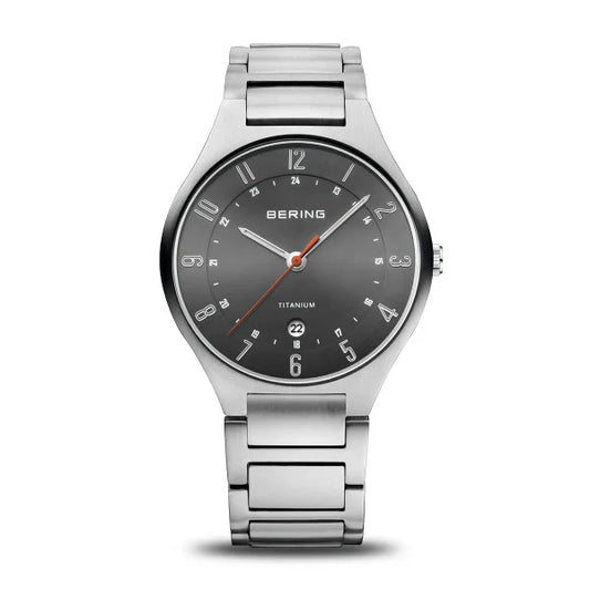 The Bering Watch - Ultra-Light Titanium Collection 11739-772 features a silver case, grey face with sapphire crystal, silver markers and hands, orange second hand, date at 6 oclock, dual 12/24-hour display, and a metal link bracelet.