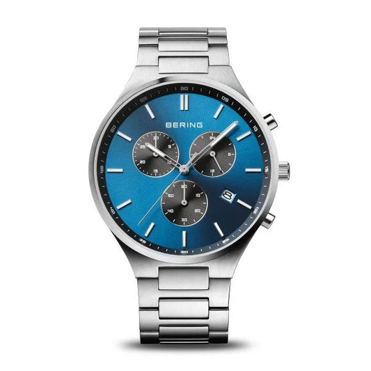 The Bering Watch - Titanium Chronograph Mens Blue w/Silver (11743-707) features a gradient blue face, three subdials, date window, minimalist hour markers, BERING branding, and a sleek stainless steel band.