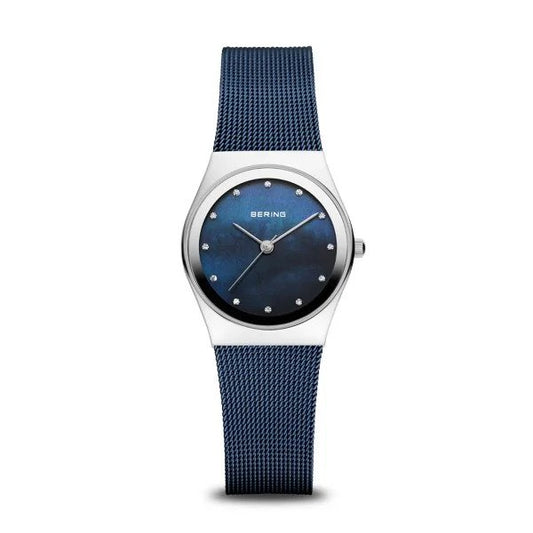 The Bering Watch - Classic Collection Womens Blue Mother of Pearl (12927-307) features a blue mesh band, round silver case, blue face with minimalist dot markers and silver hands. BERING branding is visible on the dial.