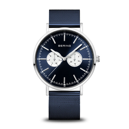 The Bering Watch - Classic Collection - 14240-300 features a blue mesh strap, dark blue dial with silver markers, two white subdials for day and date, and a polished stainless steel case in a minimalist design.