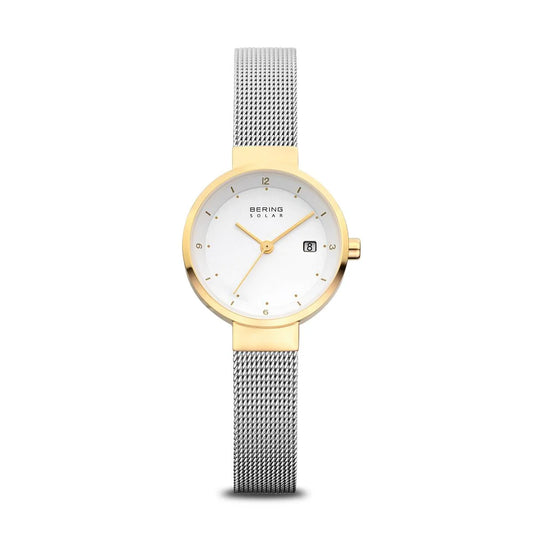 The Bering Womens Slim Solar Watch (14426-010) features a gold round case, white dial with slender gold markers, date display at 3 o’clock, silver mesh band, and eco-friendly solar movement. The Bering brand name is displayed on the dial.