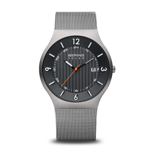 The Bering Watch - Solar Collection 14440-079 features a silver mesh band, black dial with white markers, orange seconds hand, date at 3 o’clock, durable sapphire glass, and showcases Scandinavian design.