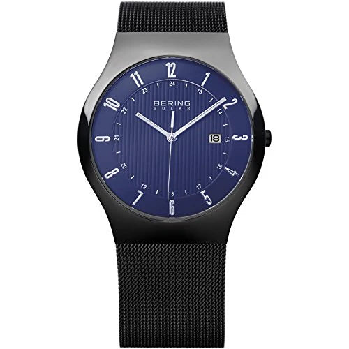 The Bering Watch - Solar - 14640-227 features a round blue dial with silver markers, white hands, date at 3 o’clock, a black mesh strap, and scratch-resistant sapphire glass for a modern minimalist look.