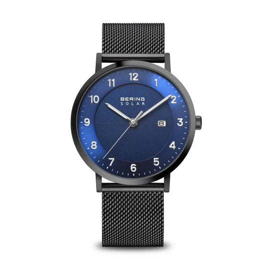 The Bering 15439-327 Slim Solar Watch features a blue dial, sapphire crystal, white hour markers, date at 3 oclock, black mesh band, solar power, and displays the Bering Solar logo at the top of the dial.