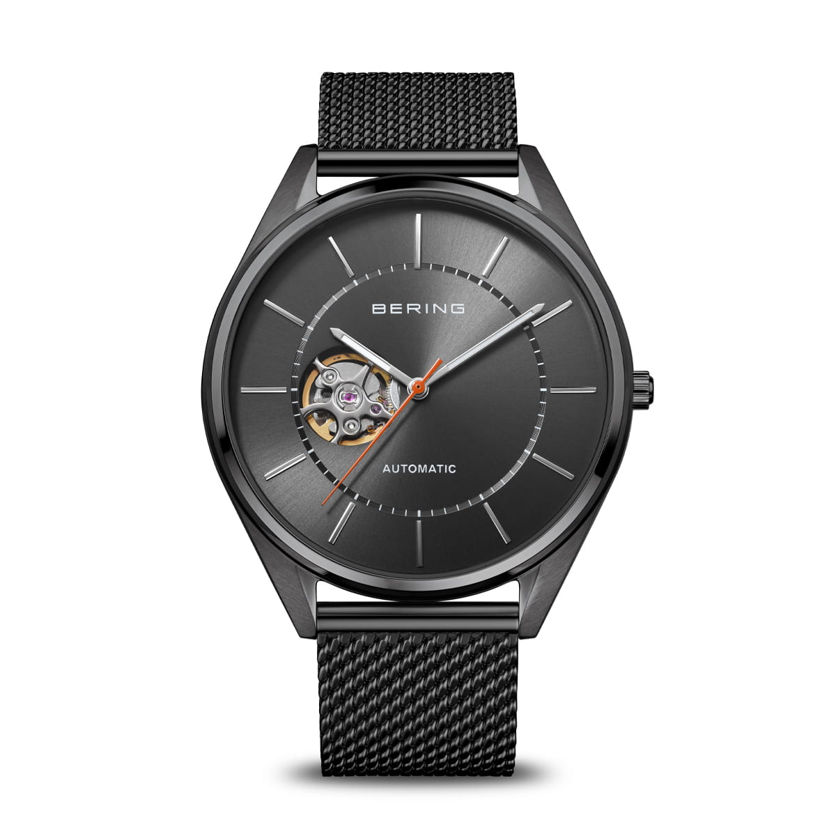 The Bering Watch - Automatic - 16743-377 by Bering features a sleek black stainless steel case, a mesh band, a minimalist dial with silver hour markers, an orange second hand, and an open heart design at 9 o’clock that reveals the watch’s automatic movement.