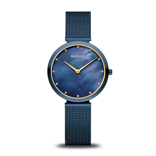 The Bering Watch - Polished Blue (18132-399) by Bering features a stylish blue round face, gold hour markers, and a blue mesh strap, elegantly displayed against a white background.
