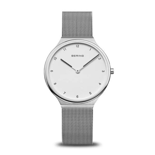 The Bering Watch - Ultra Slim Womens Silver (18434-004) features a white dial, black hour markers, silver hands, and a sleek mesh band—showcasing Bering’s minimalist elegance against a plain white background.