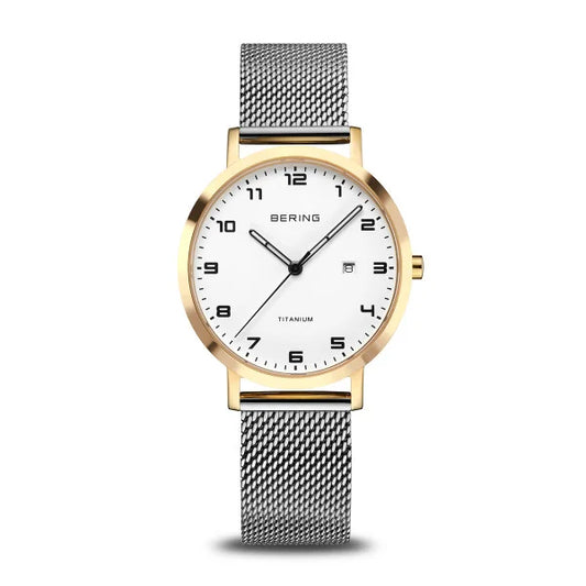 The Bering Watch - Womens Titanium - 18634-010 features a silver mesh strap, gold bezel, white face, black numerals and hands, date display, sapphire crystal, and TITANIUM above 6 o’clock. Brand: Bering.