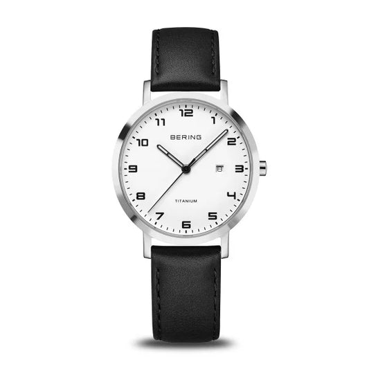 The Bering Watch - Ladies Titanium Collection (18634-404) is a minimalist ladies’ timepiece with a white dial, black Arabic numerals, date display, silver case, and black calfskin leather strap by Bering.