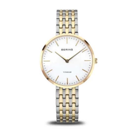 The Bering Watch - Titanium Womens Two-Tone (19334-010) features a white face, gold hour markers, and a silver and gold metal link band. Simple and elegant, it displays lines for hours and minutes only.