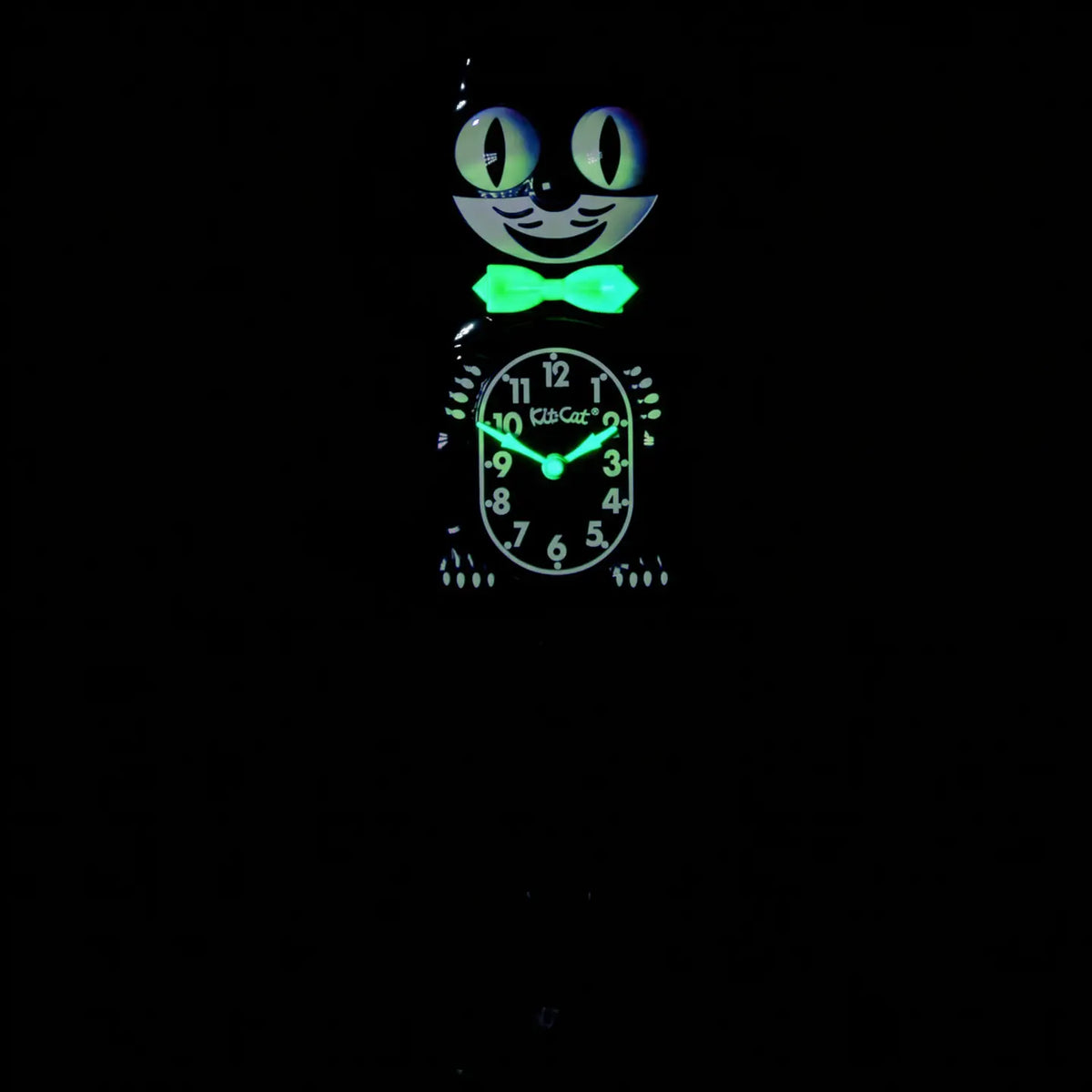 The California Clocks Kit-Cat Klock - Classic Black Gentleman Glow Edition (BC-1 GLOW) features a bow tie and glowing eyes that stand out in the dark. Illumined with a greenish light, its face and details make it easy to read the time—around 9:03—even at night.